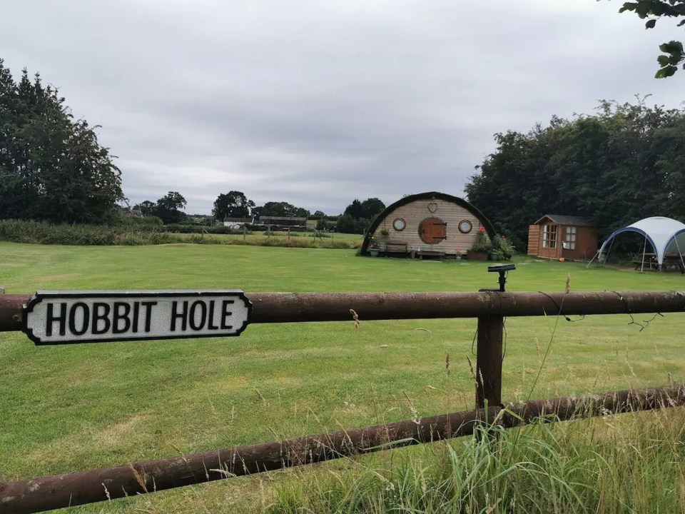 a sign on a fence that says hobbit hole