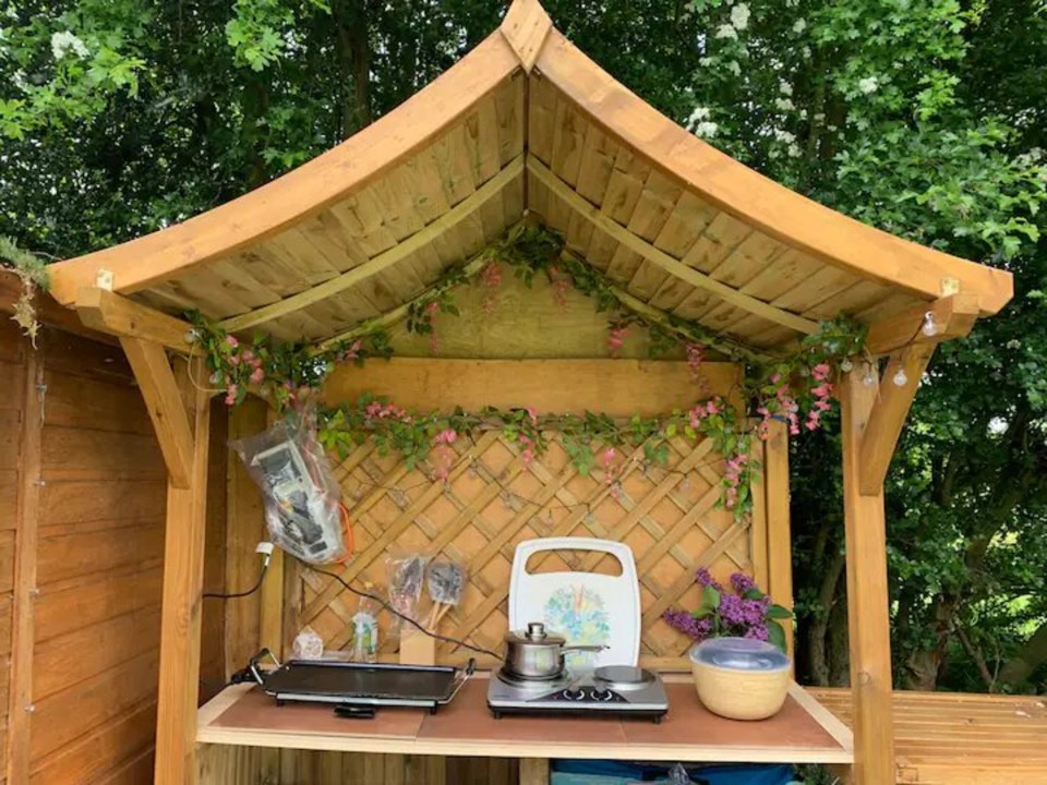 a wooden shed with a stove top oven and pots and pans on it