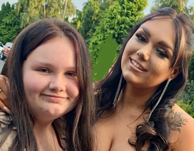 two women are posing for a picture and one is wearing a blue dress