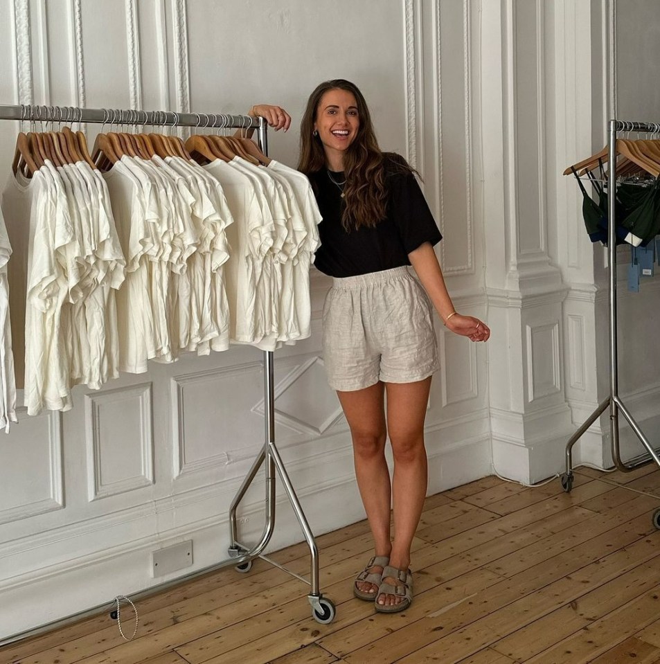 a woman stands in front of a rack of white shirts