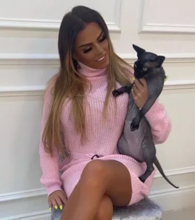 a woman in a pink sweater is sitting on a chair holding a cat