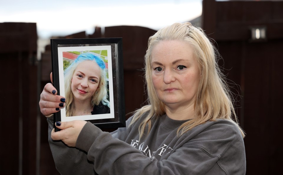 a woman holding a framed picture of a girl with blue hair