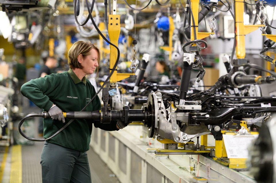 a woman working in a factory wearing a shirt that says ' stella artois ' on it