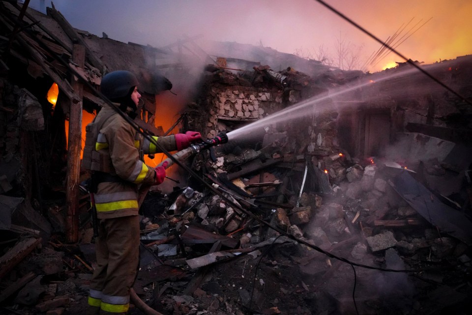 A Ukrainian rescuer works to extinguish a fire in a building following a Russian drone attack in Mykolaiv