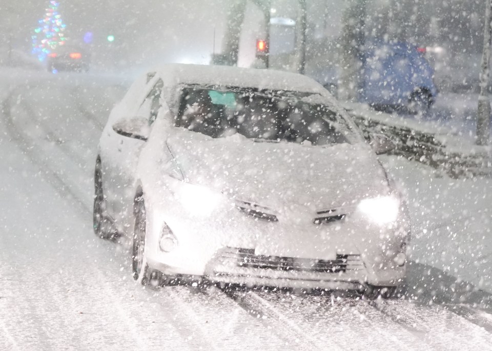 a red car is driving down a snowy road