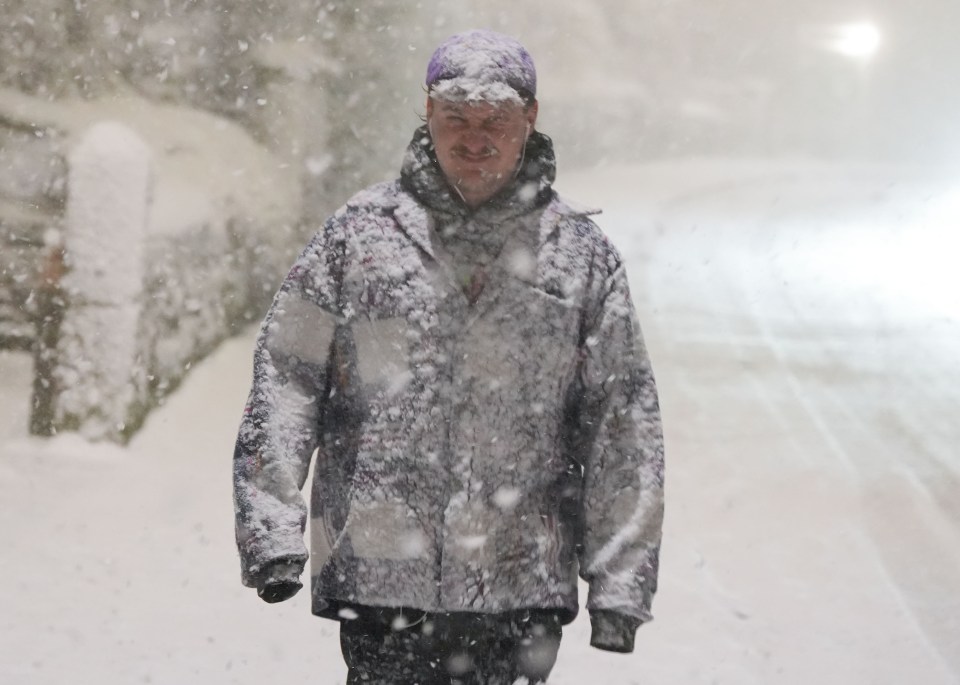 a man in a purple hat is walking in the snow