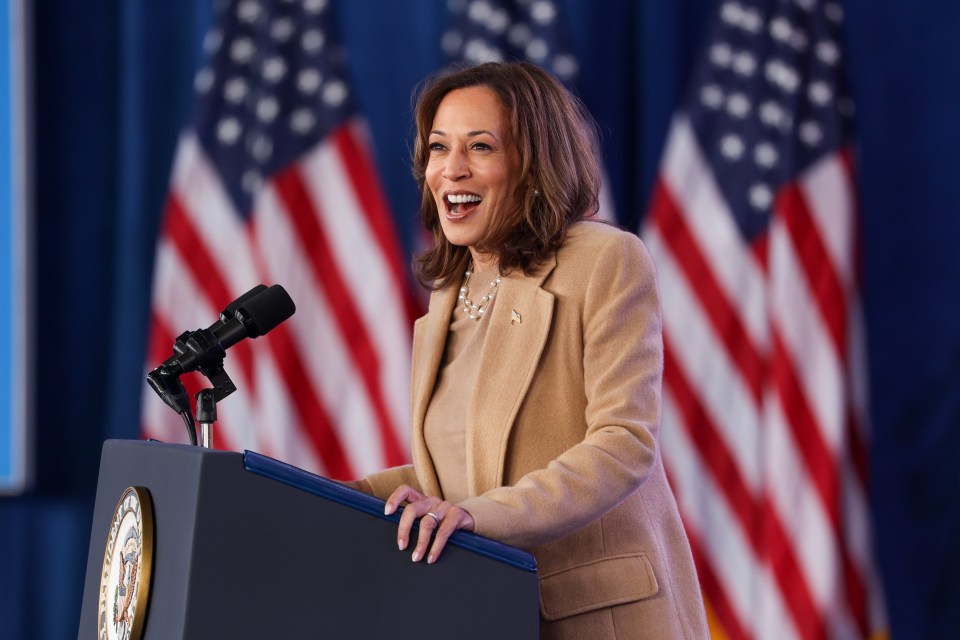 a woman stands at a podium with an american flag in the background