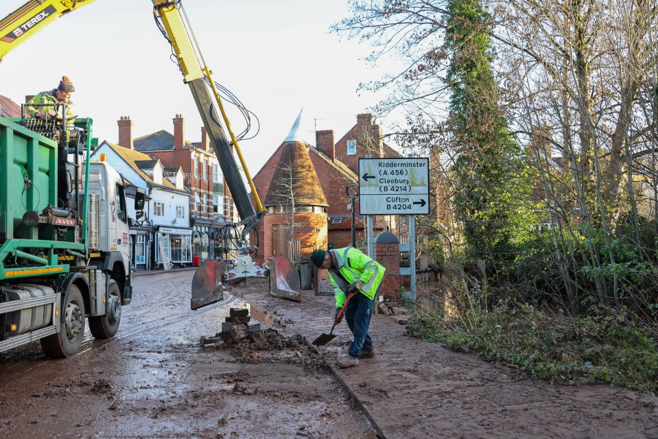 Workers attempt to shift piles of mud off the streets