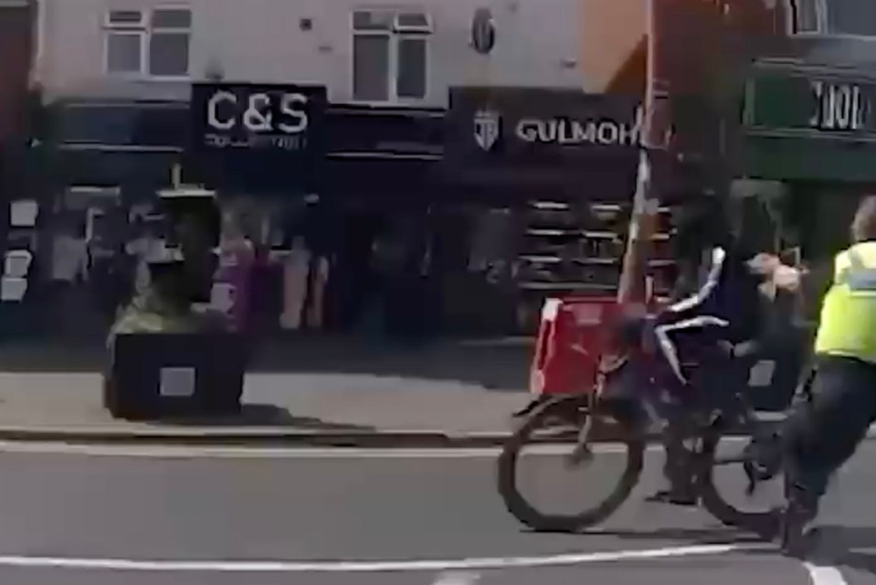 An officer for West Midlands Police is seen grabbing the cyclist’s backpack