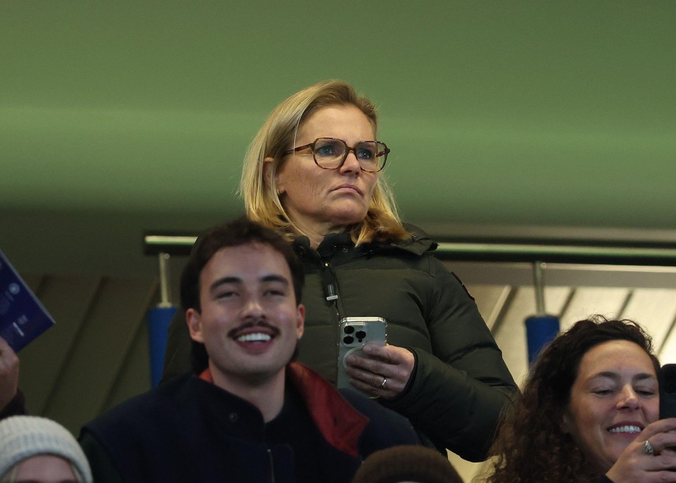 a woman wearing glasses holds a cell phone in her hand