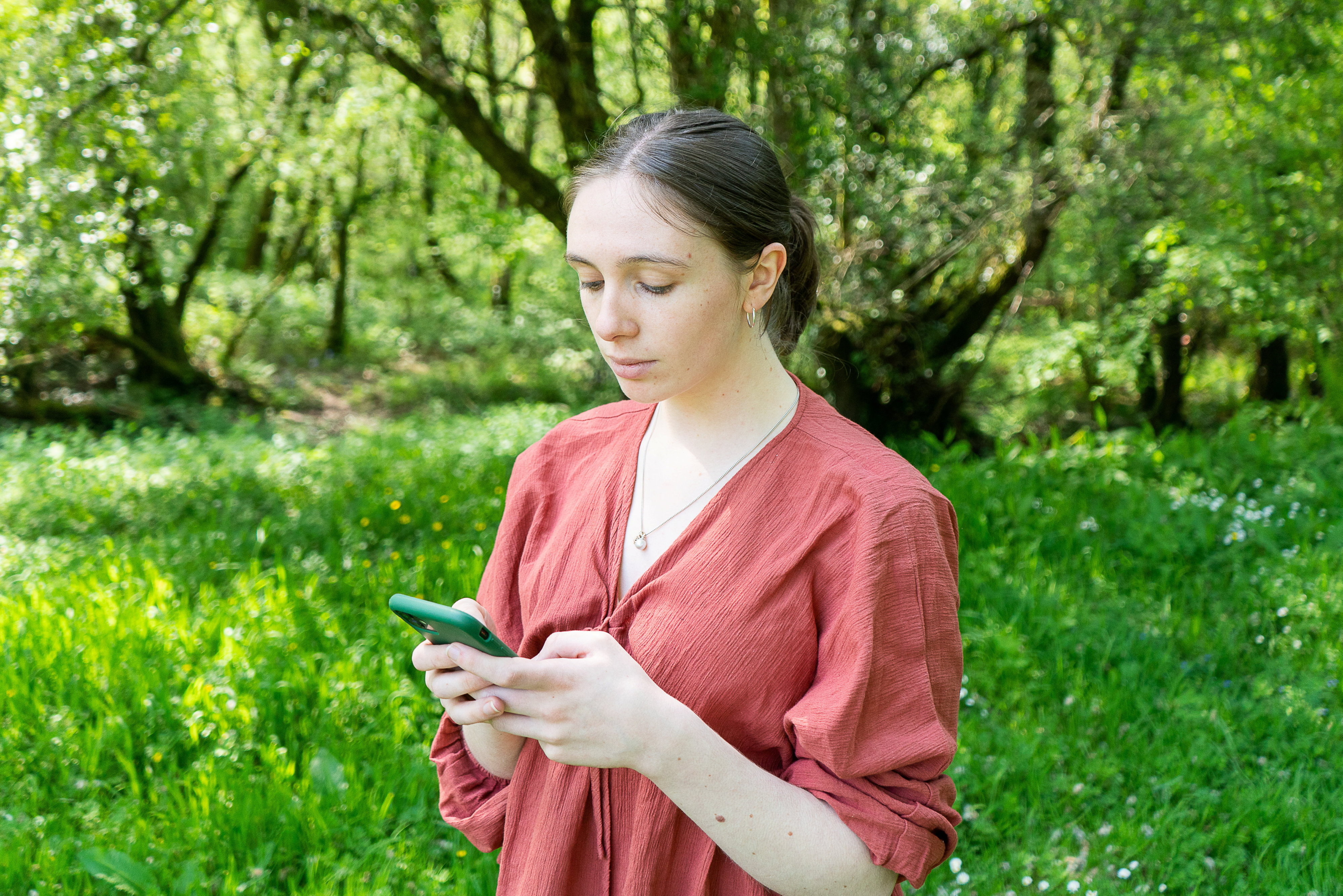 a woman in a red shirt is looking at her phone