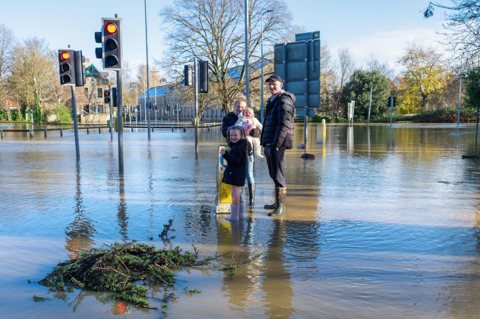 A family standing in flood water at the Bridge centre roundabout in Chippenham, Wiltshire