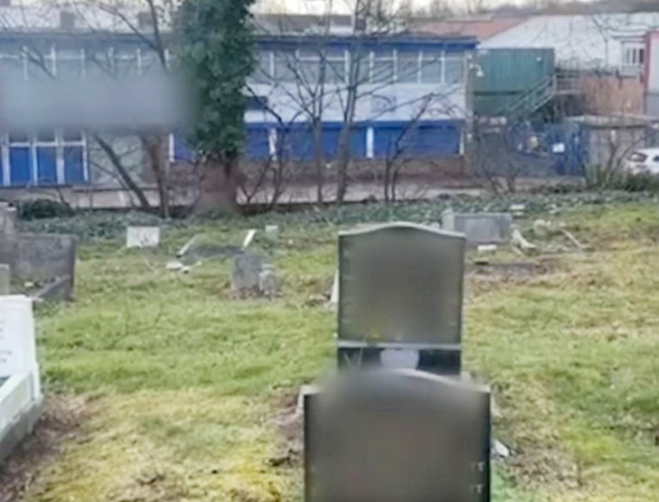 a cemetery with a lot of graves and a building in the background .