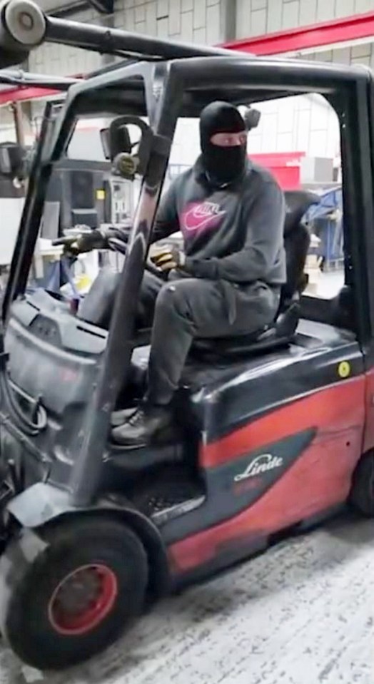 a man wearing a mask is driving a forklift in a factory .