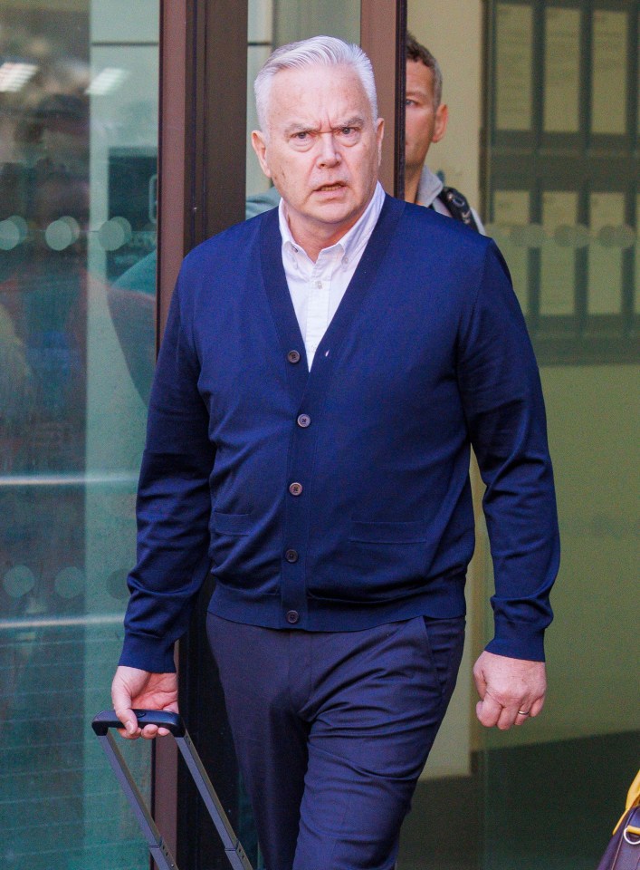 a man in a blue cardigan is holding a suitcase