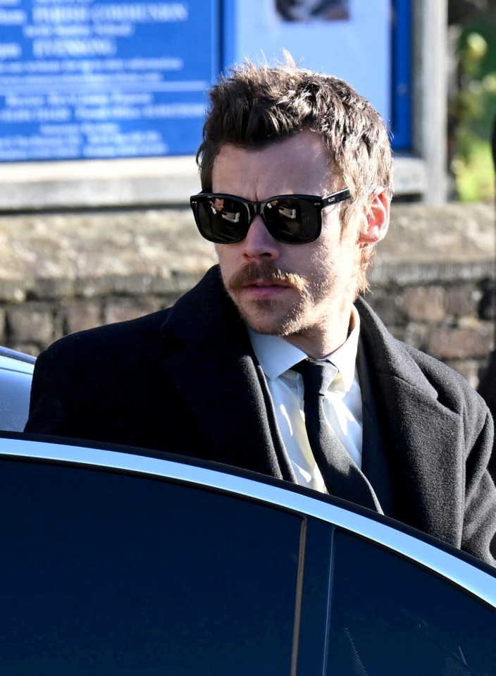 a man wearing sunglasses and a mustache is sitting in a car