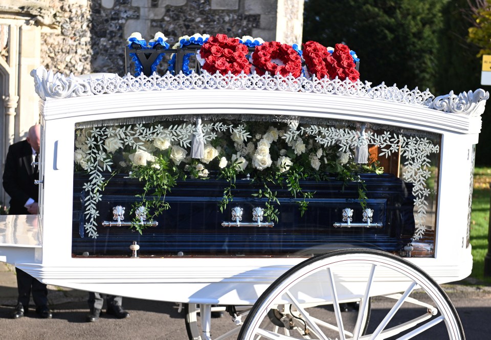 a white horse drawn carriage with a black coffin in it