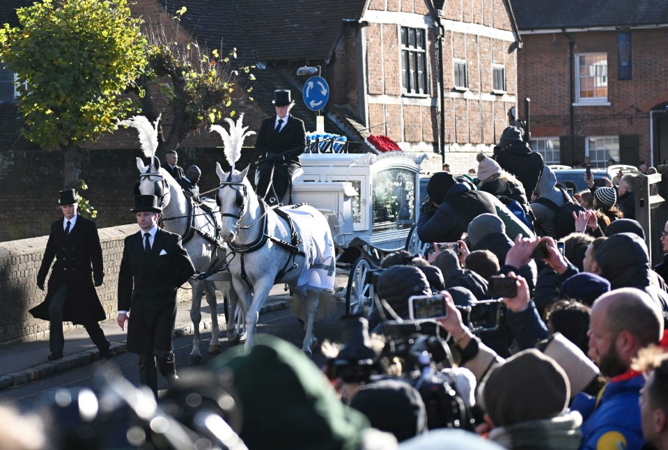 a horse drawn carriage is pulled by two men in top hats