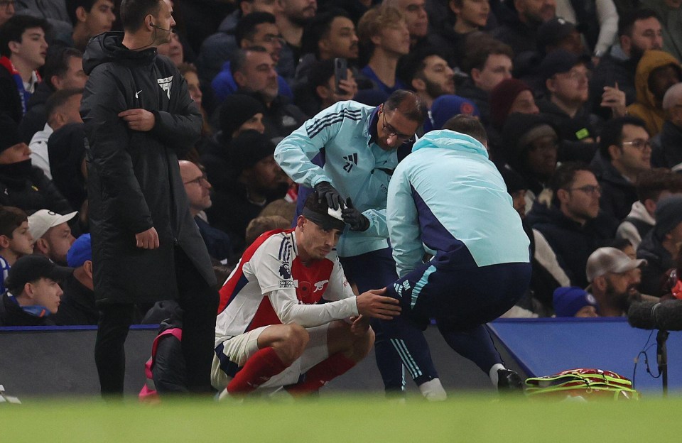 a soccer player is being helped on the field by a man wearing an adidas jacket