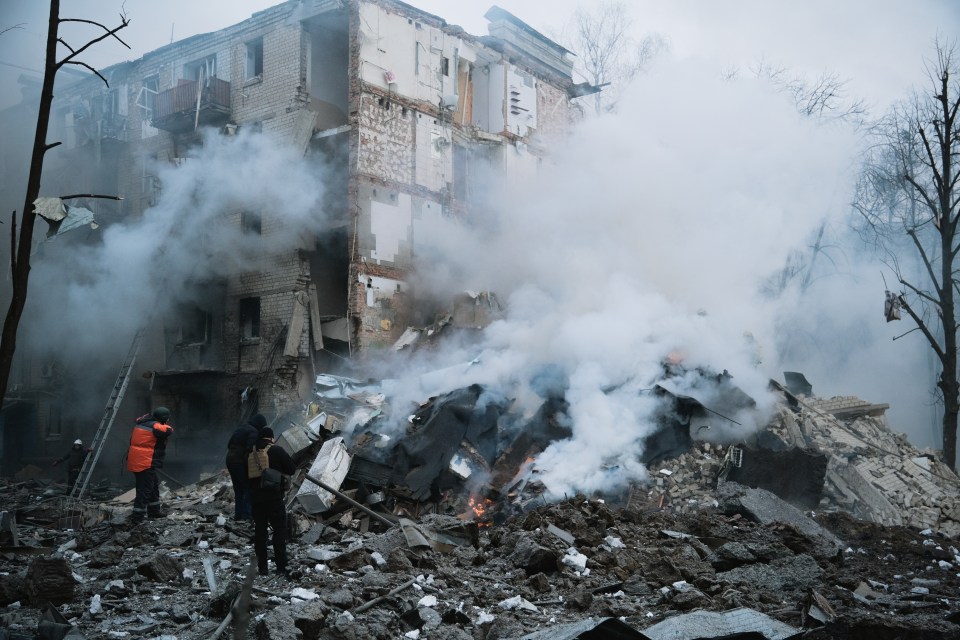 Rescuer and policemen stand amid rubble near collapsed wall of residential building after missile attack in Ukraine