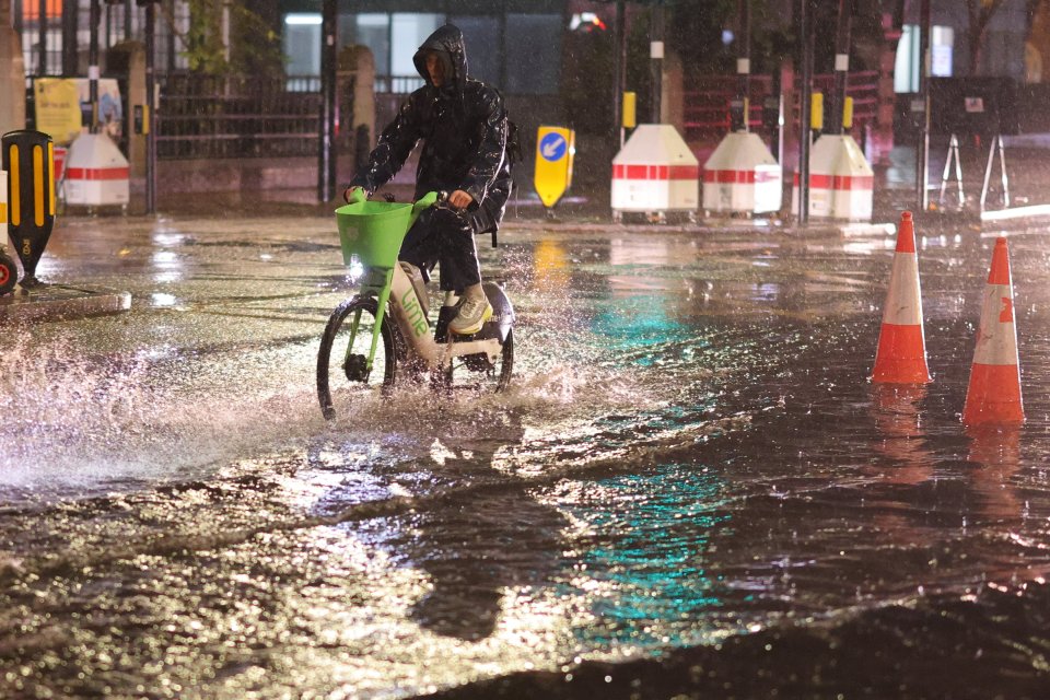 A cyclist navigates deep surface water on the Euston Road in Central London