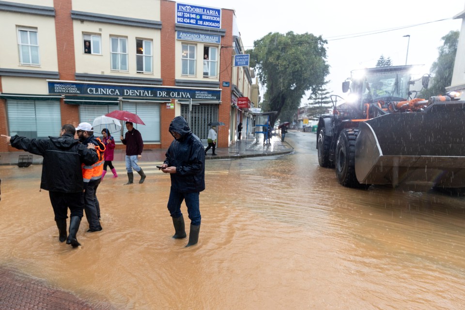 people walking through a flooded street in front of clinica dental dr. oliva