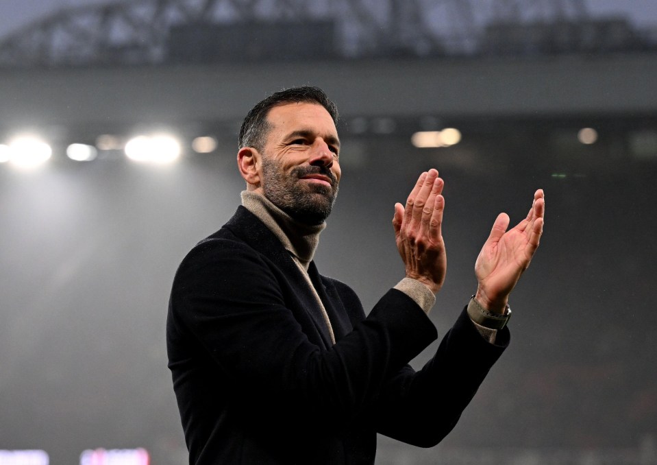 a man with a beard is clapping his hands on a soccer field