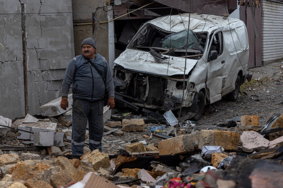 a man stands in front of a wrecked white van