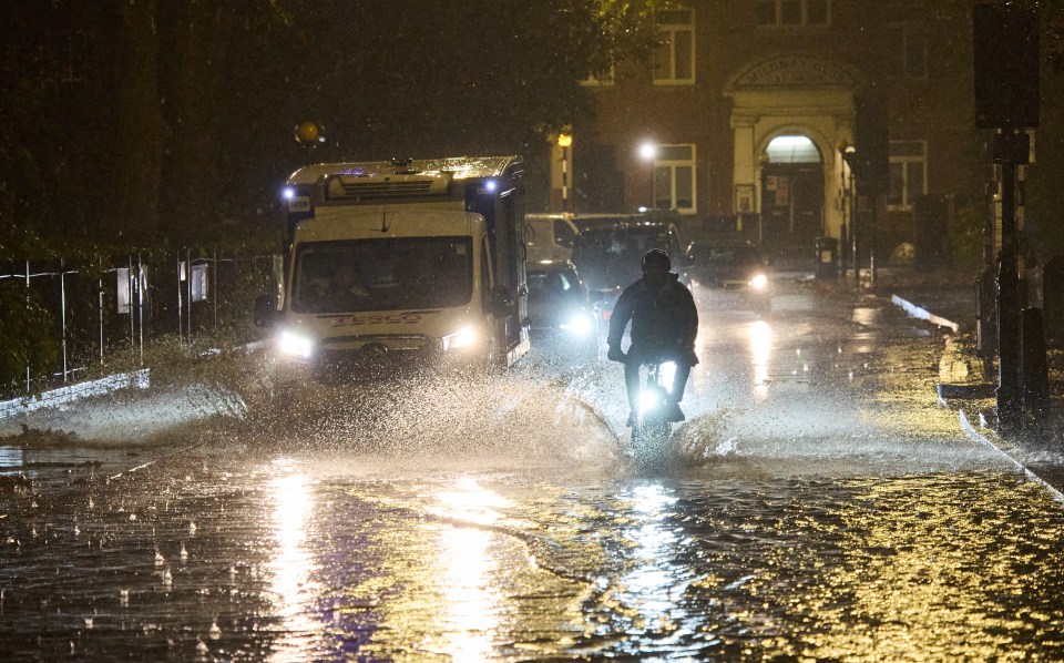 Commuters drive through a flooded Newington Green in North London