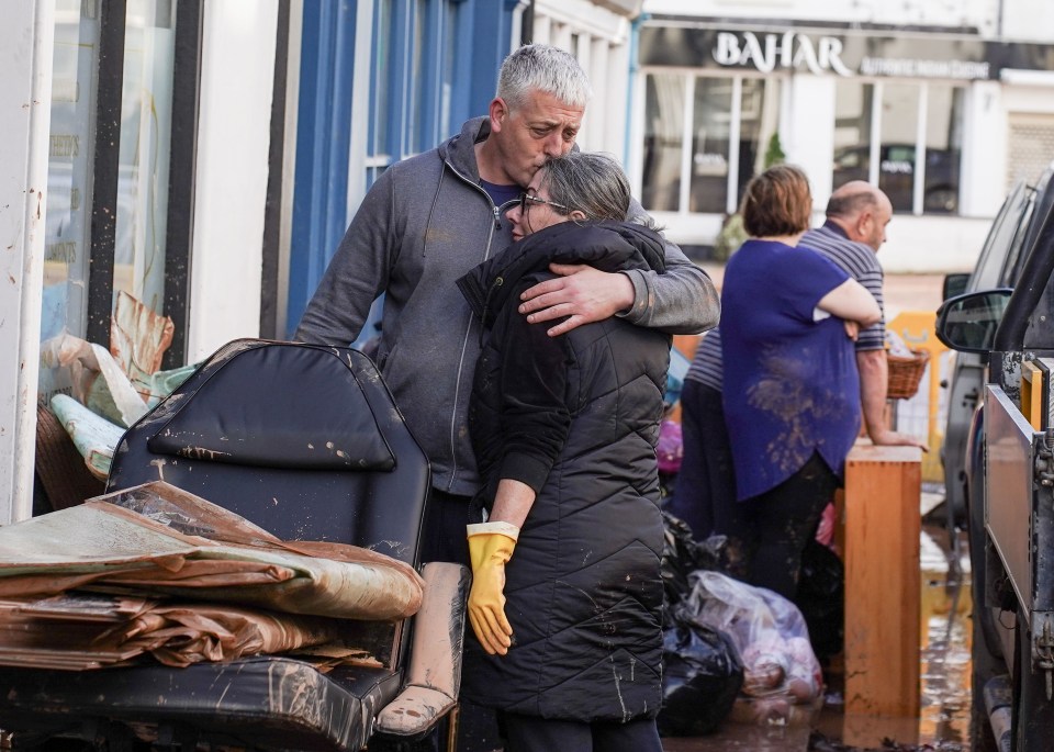 Two shop owners console each other as they clear furniture from their flood damaged property in Tenbury Wells, Worcestershire