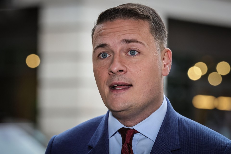 a man in a blue suit and red tie looks at the camera