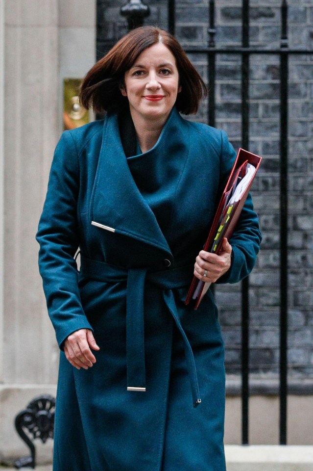 a woman in a blue coat is smiling and holding a folder