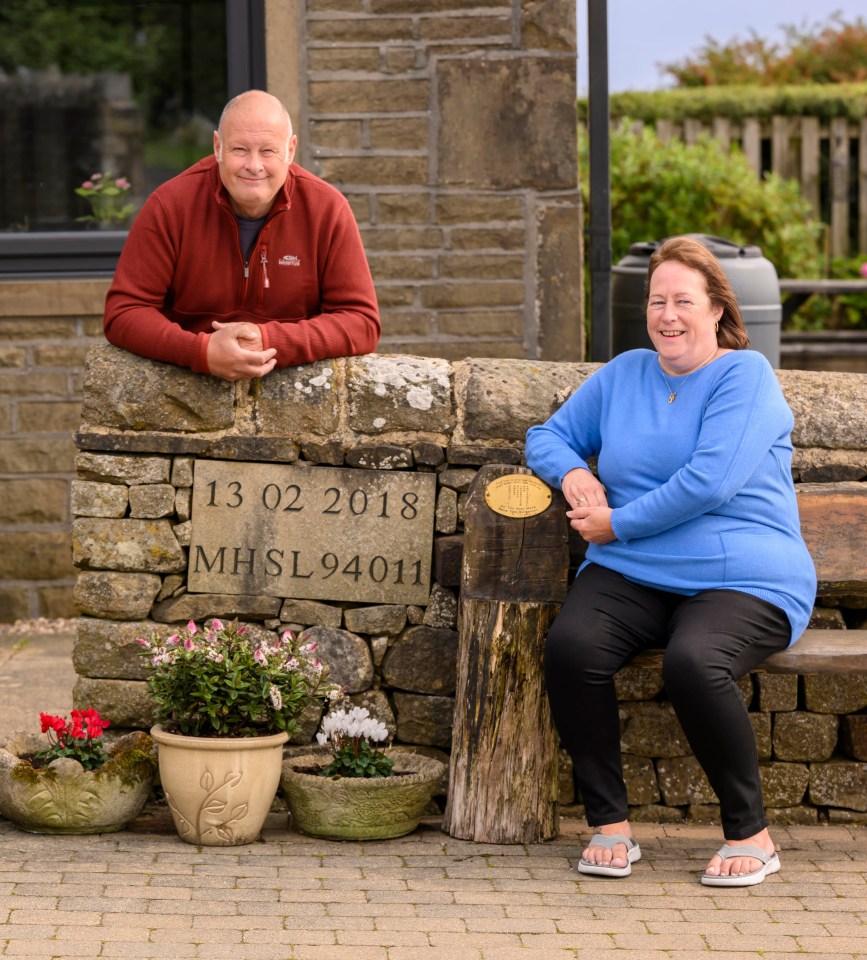 a man and a woman lean against a stone wall with the date 13 02 2018 on it