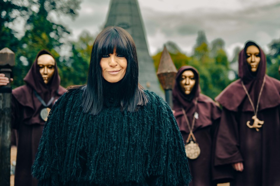 a woman in a black sweater stands in front of a group of monks