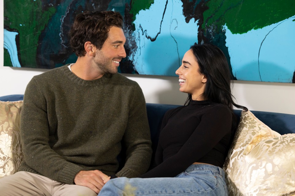 a man and a woman are sitting on a couch looking at each other