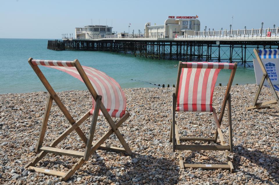 two beach chairs on a rocky beach in front of a pier amusements building