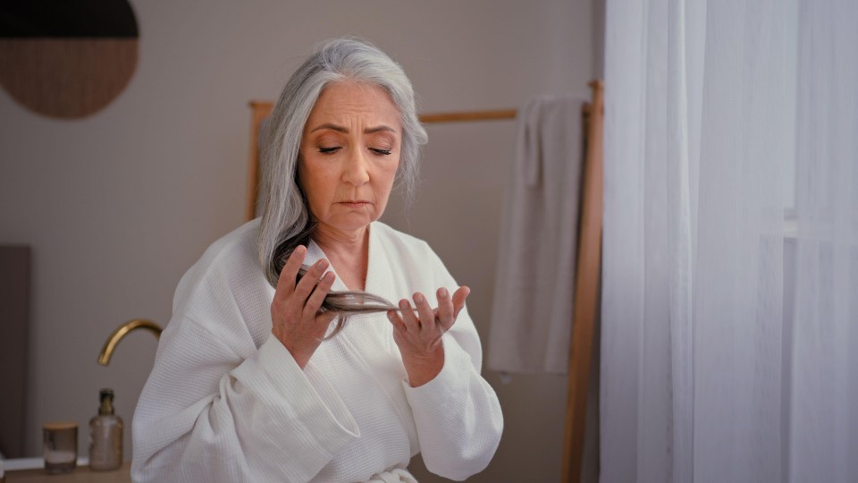 a woman with gray hair is brushing her hair in front of a mirror