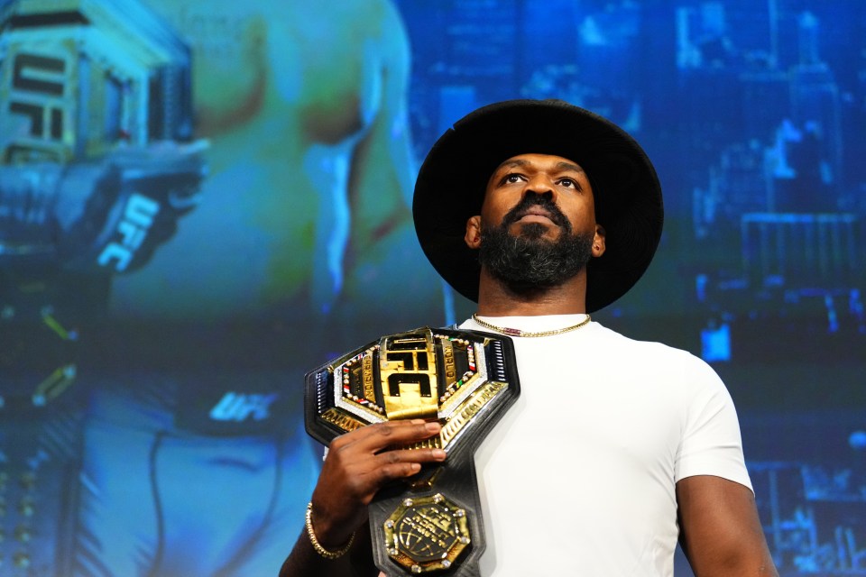 a man in a hat is holding a ufc championship belt