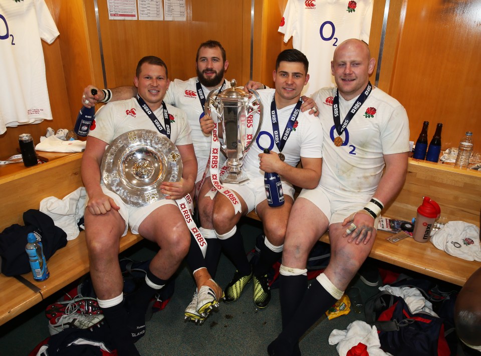 a group of rugby players holding a trophy in a locker room