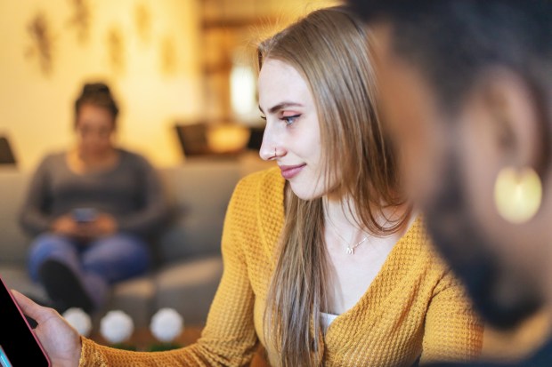 a woman in a yellow sweater is looking at a tablet