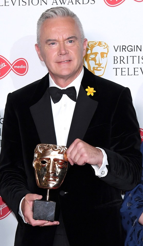 three people holding trophies in front of virgin media british academy television awards