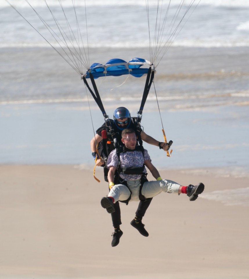 a man is carrying another man in a parachute over the beach