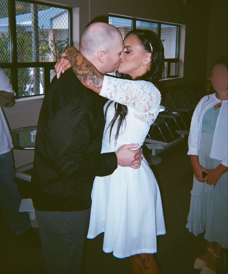 a man in a black shirt kisses a woman in a white dress