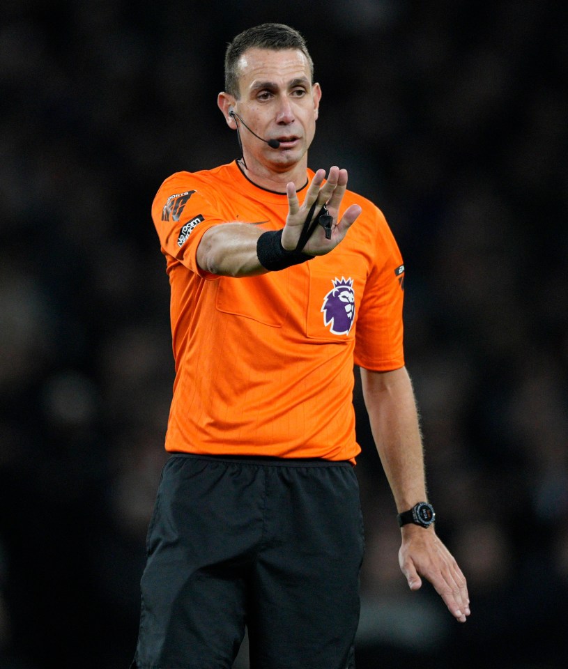 a referee wearing an orange shirt with the word premier league on it