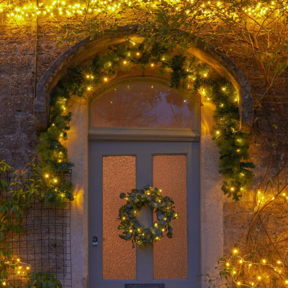 a door is decorated with a wreath and christmas lights