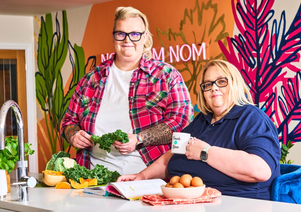 two women standing in front of a wall that says nom nom