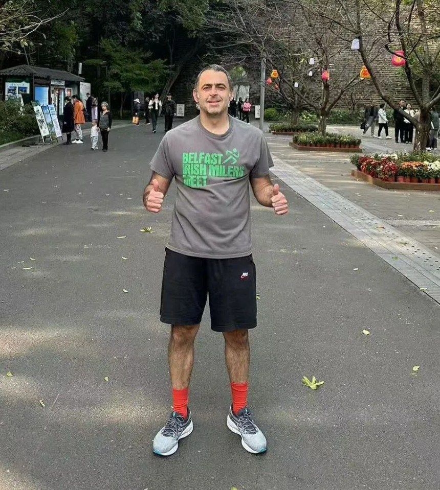 a man wearing a belfast rugby valley shirt stands in a park