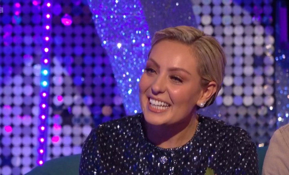 a woman is smiling in front of a bbc logo