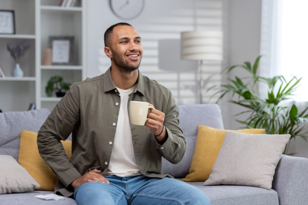 a man sits on a couch holding a cup of coffee