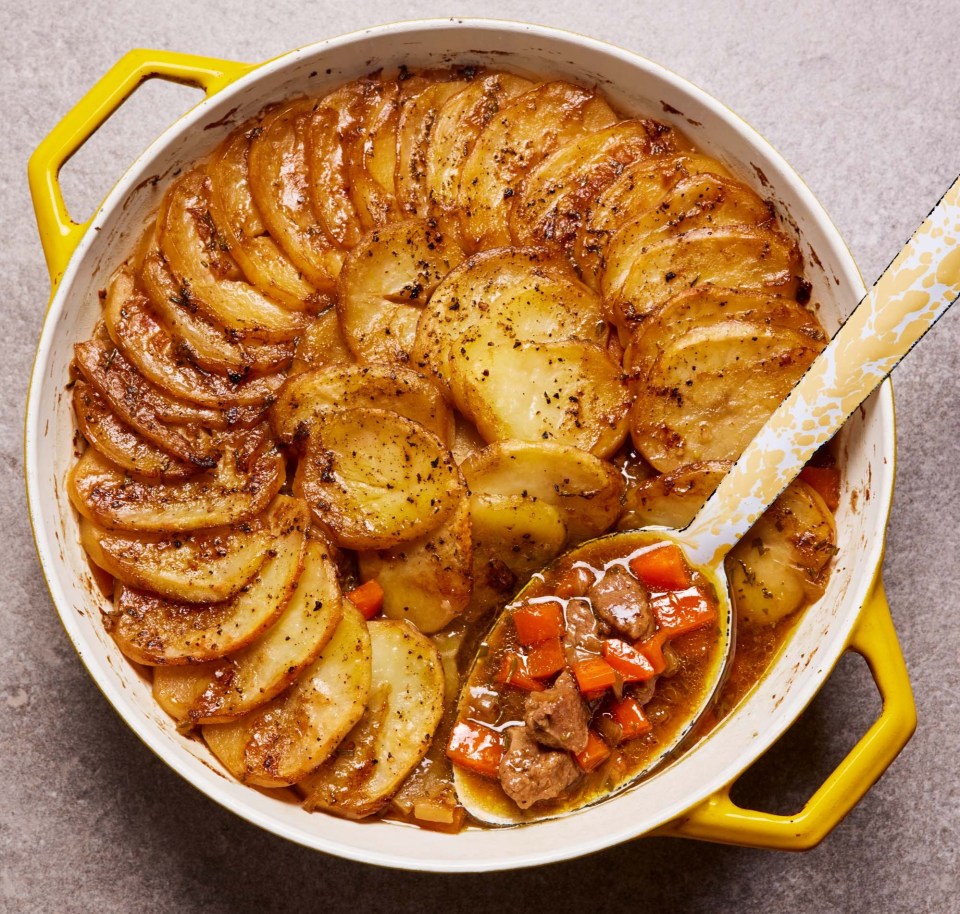 a casserole dish filled with potatoes and carrots with a spoon in it